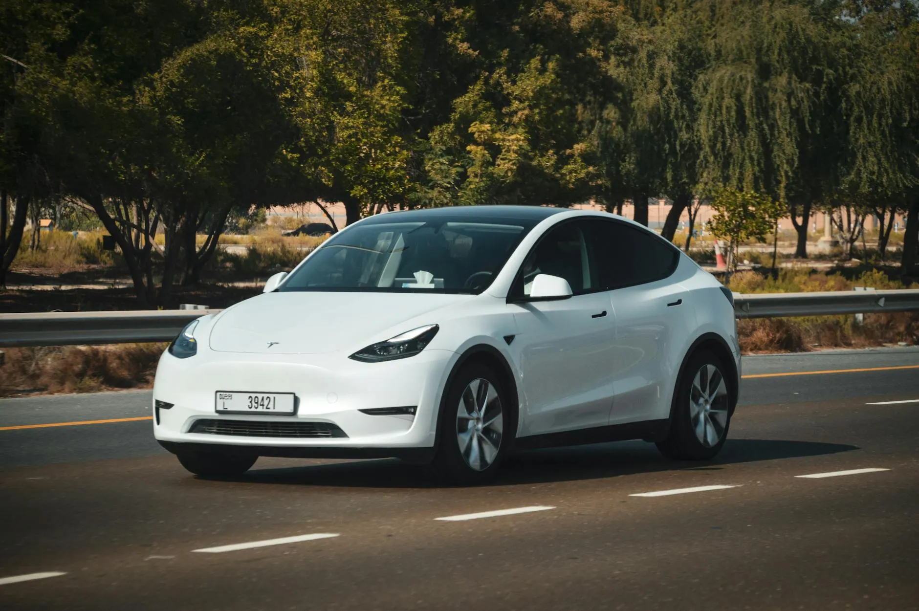 Premium electric vehicle parked in Dubai desert landscape under intense summer sun